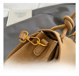 Detail of golden metal hook and knotted shoulder strap on khaki pebble leather bag