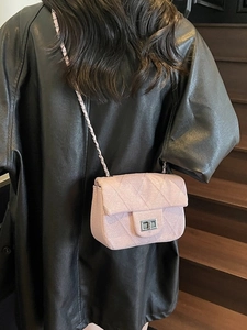 Pink quilted tweed chain bag with silver lock worn over a black leather jacket