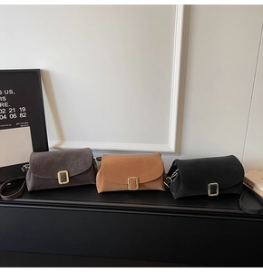 Detailed view of matte suede crossbody bags in gray, brown, and black with gold buckles