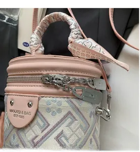 Détail du sac seau en jacquard rose avec poignée en foulard et doubles fermetures éclair