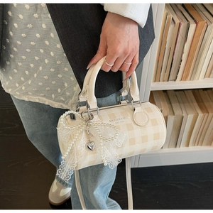 Détail du sac polochon à carreaux avec nœud en perles et breloque cœur sur métal argenté