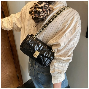 Close-up of black quilted crossbody bag with gold chain strap worn by a model