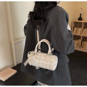 Détail du sac Boston à carreaux crème avec nœud en dentelle et breloque en perles