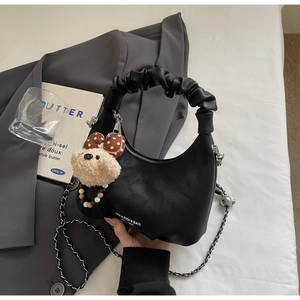 Detail einer schwarzen Hobo-Tasche mit Falten-Griff, Silberkette und Plüschbär-Anhänger