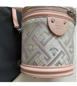 Détail du motif jacquard et des garnitures en cuir rose sur le sac seau avec logo