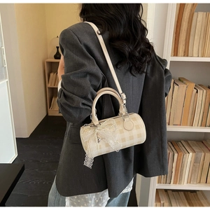 Detailed view of beige checkered cylindrical bag with pearl and lace bow decorations
