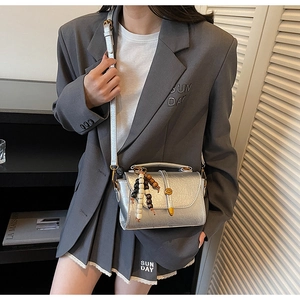 Détail du petit sac argenté texturé avec boucle de ceinture et pompon en perles chic
