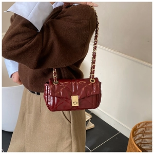 Close-up of burgundy quilted leather crossbody bag with golden chain and metal clasp