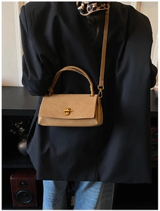 Detail of khaki faux suede crossbody bag with gold twist lock and adjustable shoulder strap