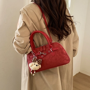 Detail of burgundy frosted boston bag with silver hardware and plush bear charm