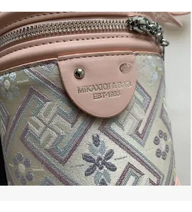Détail macro de la texture du cuir rose et du tissu jacquard sur le sac seau