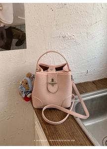 Detailed view of pink croc-embossed bucket bag with bear charm and silver twist lock