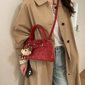 Detail of red frosted retro Boston bag with bear charm on a trench coat model