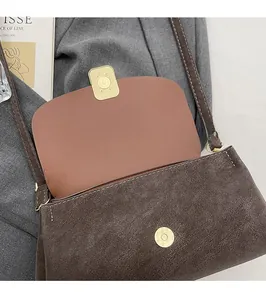 Detail of the golden magnetic buckle and suede texture on this brown crossbody bag