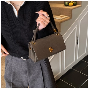 Detail of grey suede square handbag with knotted handle and gold metal twist lock closure