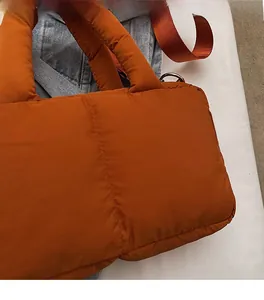 Detail of soft quilted orange nylon fabric and vertical stitching on the cloud tote bag