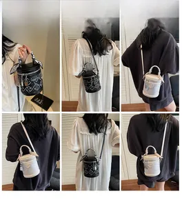 Détail du sac seau cylindrique avec motifs géométriques et poignée décorée d'un foulard