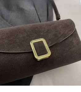 Close-up of matte dark brown leather texture with elegant gold rectangular metal buckle