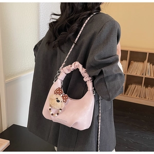 Detail der rosa Hobo-Tasche mit Wolkengriff und Plüschbär-Anhänger auf grauem Anzug