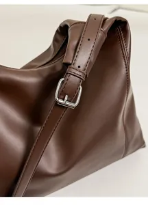 Detail of dark brown leather tote with silver buckle and textured adjustable strap