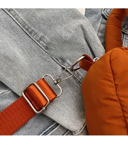 Close-up of bright orange quilted bag with silver lobster clasp and fabric shoulder strap
