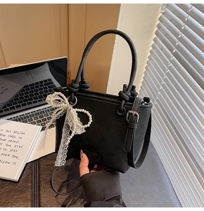 Détail d'un sac seau en cuir noir avec nœud en perles et bandoulière réglable