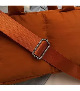 Detail of adjustable nylon strap and silver buckle on orange quilted shoulder bag