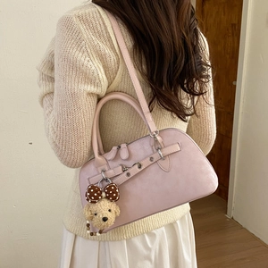 Pale pink Boston bag with textured finish and cute plush charm on beige sweater