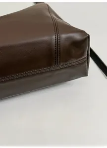 Detail shot of deep brown leather tote showing fine natural texture and double stitching