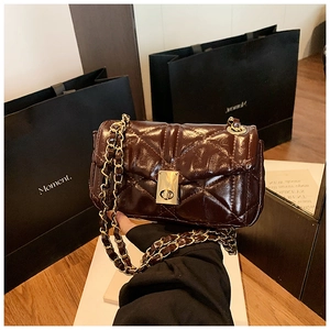 Detail of quilted dark coffee crossbody bag with metallic turn-lock and chain strap