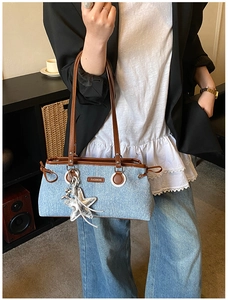 Détail du sac bowling en denim avec bordure en cuir marron et breloque étoile