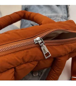 Detail of silver metal zipper and smooth stitching on caramel quilted puffer bag