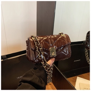 Detailed view of dark brown quilted faux leather mini bag with gold chain and twist lock