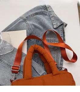 Detail of orange quilted puffer tote bag with matching fabric strap and metal hooks