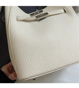 Dettaglio in pelle martellata color crema con chiusura in metallo argento della borsa