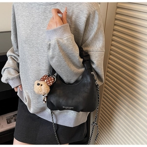 Detail der schwarzen Hobo-Tasche mit Falten Griff und süßem Bären-Anhänger