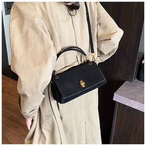 Detail view of the black matte leather crossbody bag with a gold rectangular lock