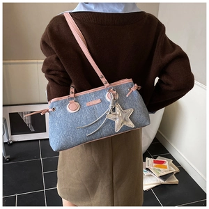 Détail du sac bowling en jean avec garniture en cuir rose et breloque étoile à l'épaule