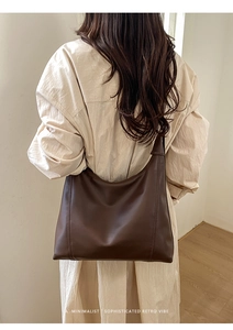 Detail of dark brown leather hobo bag with vertical stitching and wide shoulder strap