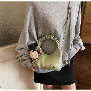 Detail der hellgrünen Handtasche mit Falten Griff, Plüschbär-Anhänger und Kettengurt