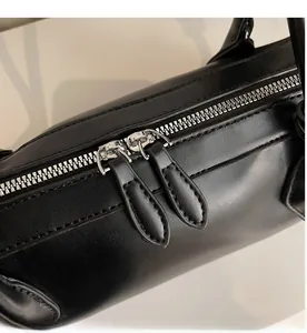 Détail des doubles fermetures éclair en métal argenté et coutures sur sac en cuir noir