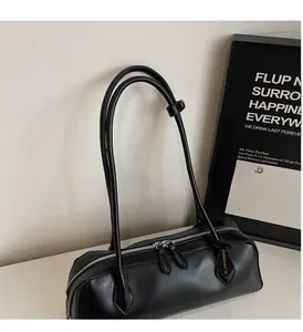 Détail d'un sac cylindrique en cuir noir avec longues anses et double zip argenté