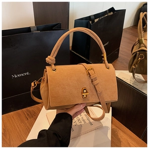 Detail of khaki suede crossbody bag featuring gold twist-lock and top handle