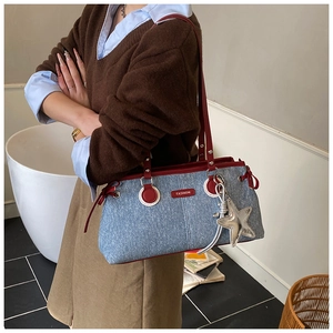 Gros plan du sac bowling en denim avec bordures en cuir rouge et pendentif étoile