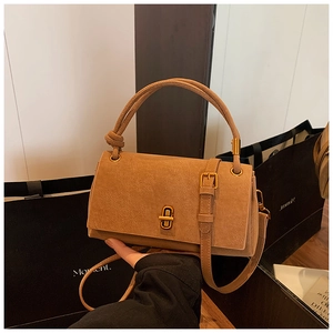 Detail of camel suede crossbody bag featuring gold twist lock and elegant knot handle