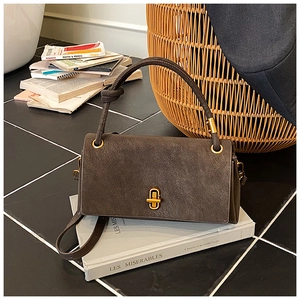 Detail of elegant dark grey crossbody bag with gold twist lock on top of vintage books