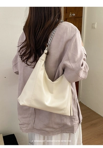 Close-up of minimalist cream leather shoulder bag with silver chunky chain strap detail