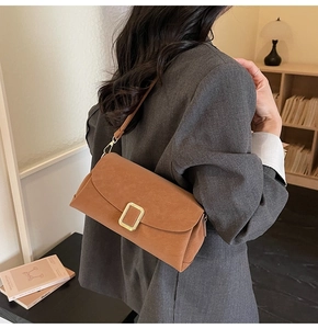 Detail of vintage brown suede shoulder bag with rectangular metal buckle and slim strap