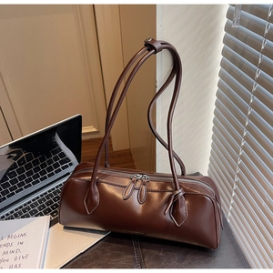 Gros plan d'un sac baguette cylindrique marron foncé avec double fermeture éclair