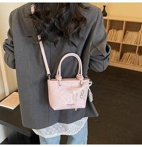 Détail du sac seau rose avec nœud en dentelle, pendentif cœur et texture cuir